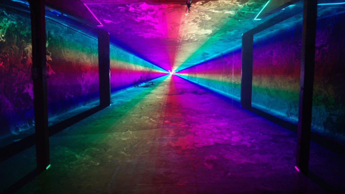 Solid rainbow laser light tunnel shines through an empty nightclub past four silhouetted columns. Alpha matte background 